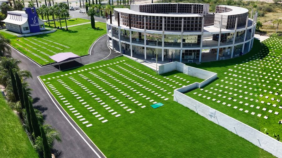 Vista aérea del cementerio Jardines Perpetuos: el edificio circular de mausoleos, las áreas verdes con placas y las vialidades con palmeras