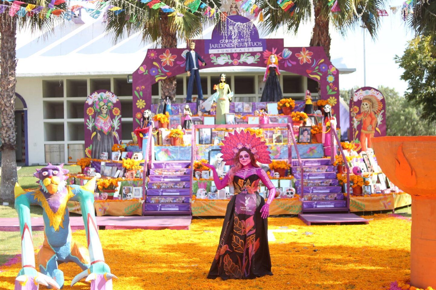 Altar monumental del Festival de Día de Muertos de Jardines Perpetuos: una catrina posa al frente sobre una alfombra de cempasúchil