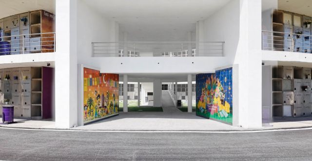 Paso hacia el patio interior del edificio de nichos, flanqueado por dos murales de colores con motivos de Día de Muertos
